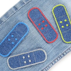 Könnte beinhalten: Vier Pflaster aus Jeansstoff mit verschiedenen farbigen Nähten. Die Pflaster sind blau mit roten, gelben, blauen und weißen Nähten.