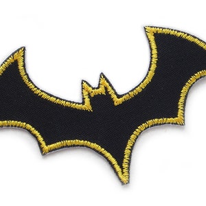 Könnte beinhalten: Schwarzer Fledermaus-Patch mit gelber Umrandung. Der Patch ist aus Stoff und hat ein gesticktes Design.