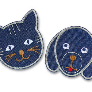 Könnte beinhalten: Zwei Jeans-Patches: eine Katze und ein Hund. Der Katzen-Patch hat weiße Augen, Schnurrhaare und eine Nase mit hellblauen Konturen. Der Hunde-Patch hat weiße Augen, eine Nase und eine rote Zunge mit hellblauen Konturen.