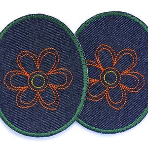 Op de afbeelding: Twee denim patches met een groene gestikte rand en een oranje geborduurd bloemenontwerp.
