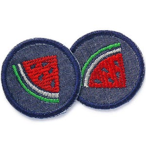 Può includere: Due toppe rotonde in denim blu con cuciture bianche. Ogni toppa presenta una fetta di anguria ricamata in rosso, verde e bianco.
