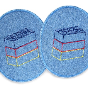 Op de afbeelding: Twee blauwe denim patches met geborduurde afbeeldingen van een stapel kleurrijke speelgoedbouwstenen. De blokken zijn gestapeld in drie rijen met gele, rode en blauwe accenten.