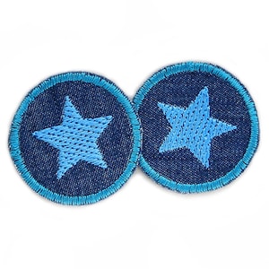 Könnte beinhalten: Zwei blaue Jeans-Patches mit einem hellblauen Stern, der auf jedem gestickt ist. Die Patches haben einen hellblauen Rand.