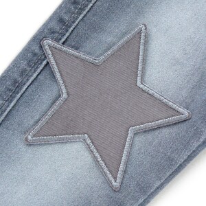 Puede incluir: Un par de pantalones vaqueros azules con un parche en forma de estrella gris cosido en la parte delantera.