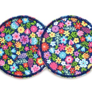 Könnte beinhalten: Zwei runde, marineblaue Stoffpolster mit einem bunten Blumenmuster. Die Polster haben einen rosa und weißen genähten Rand.