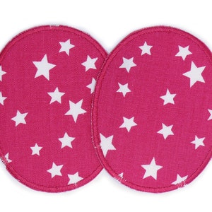 May include: Two pink fabric nursing pads with white stars printed on them. The pads are round and have a white stitched edge.