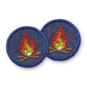 Può includere: Due toppe ricamate circolari con un disegno di falò. Ogni toppa ha uno sfondo in denim blu e un'immagine dettagliata di fiamme rosse, arancioni e gialle, con tronchi marroni alla base.