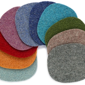 Op de afbeelding: Een set van tien vilt cirkels in verschillende kleuren, waaronder oranje, rood, paars, blauw, groen en grijs. De cirkels zijn in een halve cirkel gerangschikt, met de grootste cirkel onderaan en de kleinste cirkel bovenaan.