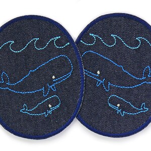 Könnte beinhalten: Zwei marineblaue Denim-Patches mit einem Design einer blauen Walfamilie. Jeder Patch zeigt einen großen Wal, einen kleinen Wal und wellenförmige Linien, alle in Hellblau gestickt. Die Patches haben einen dunkelblauen Rand.