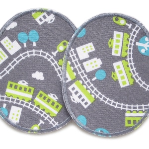 Può includere: Due cerchi in tessuto grigio con un design di treno e città. I cerchi hanno un motivo verde, bianco e blu.