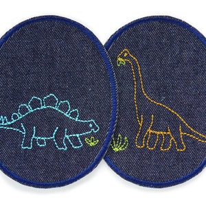 May include: Two denim patches with embroidered dinosaurs. The patch on the left features a blue dinosaur with green plants. The patch on the right features an orange dinosaur with green plants.
