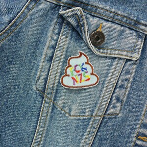 May include: A blue denim jacket with a colorful embroidered patch of a pile of poop with the word "FCK NZS" on it.