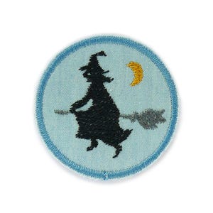 Könnte beinhalten: Gestickter Aufnäher mit einer schwarzen Silhouette einer Hexe auf einem Besen vor hellblauem Hintergrund. Ein gelber Halbmond befindet sich oben rechts. Der Aufnäher hat einen hellblauen Rand mit einem dunkelblauen, genähten Rand. Ideal für Halloween.