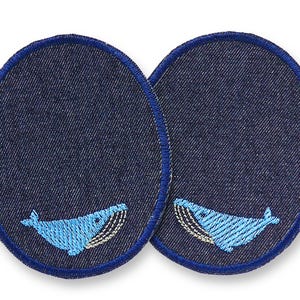 Könnte beinhalten: Zwei ovale Denim-Patches mit einer blauen Wal-Stickerei. Die Patches haben einen dunkelblauen Denim-Hintergrund mit einem blau genähten Rand. Der Wal ist hellblau mit weißen und blauen Details.