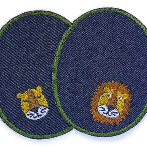 Könnte beinhalten: Zwei Jeans-Patches mit grüner Naht, jeder mit einem gestickten Löwenkopf mit gelbem und orangefarbenem Fell, weißen Zähnen und schwarzen Augen.