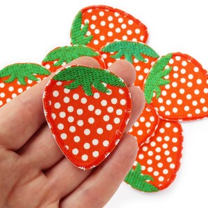 Könnte beinhalten: Ein Set aus drei Keramikbechern mit cremefarbener, gesprenkelter Glasur. Jeder Becher zeigt ein handgemaltes Blumendesign in Blau-, Grün- und Gelbtönen. Die Becher haben eine einfache, abgerundete Form und einen bequemen Griff.