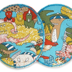 May include: Two round fabric patches with a blue background and a variety of colourful dinosaurs, including a yellow dinosaur with red spots, a blue dinosaur with white stripes, and a green dinosaur with orange spots.