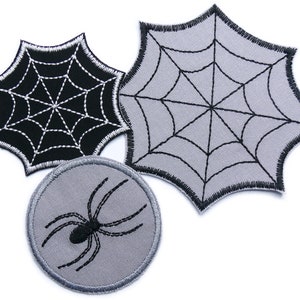 Könnte beinhalten: Drei gestickte Aufnäher mit Spinnennetz- und Spinnenmotiven. Zwei Spinnennetz-Aufnäher sind in Schwarz und Grau gehalten, einer ist rund mit einer Spinne. Geeignet für Halloween oder gruselige Projekte.