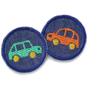 Può includere: Due toppe ricamate con un design a forma di auto. Una toppa ha un'auto verde con ruote gialle, l'altra un'auto arancione con ruote gialle. Entrambe sono su uno sfondo di denim blu scuro con un bordo blu.