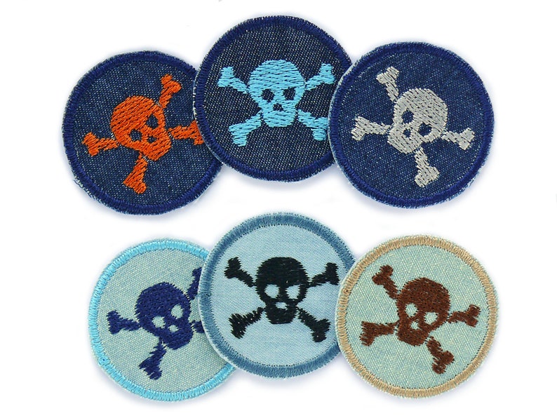 May include: Six embroidered iron-on patches featuring a skull and crossbones design. The patches are in a variety of colours, including blue, orange, grey, black, brown, and white.
