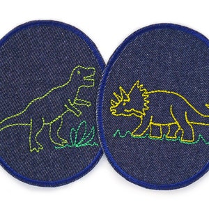 Può includere: Due toppe di jeans con dinosauri ricamati. La toppa a sinistra presenta un dinosauro verde con un contorno giallo. La toppa a destra presenta un dinosauro giallo con un contorno verde.