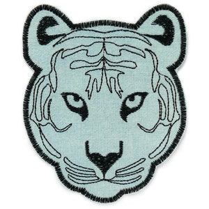 Könnte beinhalten: Ein blauer gestickter Aufnäher mit dem Gesicht eines Tigers mit schwarzen Nähten.