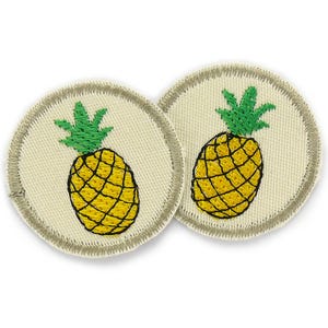 Può includere: Due toppe rotonde in tessuto beige con bordo grigio, ciascuna con un ananas giallo ricamato con foglie verdi.