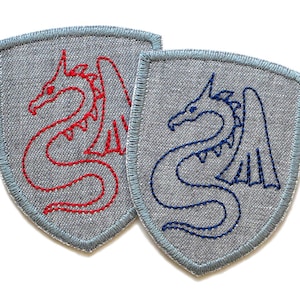 May include: Two embroidered iron-on patches in the shape of a shield. One patch features a red dragon with wings, the other features a blue dragon with wings.