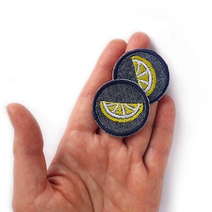Può includere: Due toppe ricamate da stirare a forma di spicchio di limone. Le toppe sono blu navy con cuciture gialle e bianche.