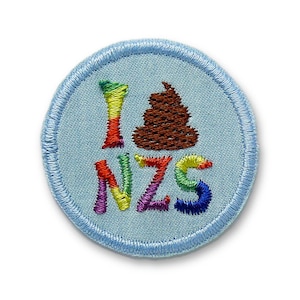 Può includere: Toppa ricamata con sfondo azzurro chiaro e bordo cucito blu. La toppa presenta le parole "I NZS" nei colori dell'arcobaleno, con un'emoji di cacca marrone che sostituisce il simbolo del cuore.