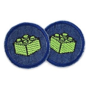Könnte beinhalten: Zwei blaue Jeans-Patches mit einem grünen gestickten Lego-Stein-Design.