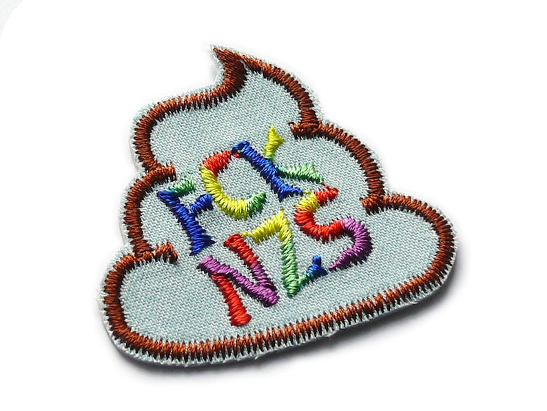May include: A brown embroidered patch shaped like a pile of poop with the word "FCK NZS" written in rainbow colors.