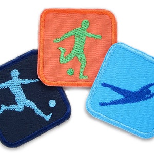 Könnte beinhalten: Drei gestickte Bügelbilder mit verschiedenen Fußballspielern in verschiedenen Posen. Die Patches sind quadratisch und haben einen blauen, orangen und hellblauen Hintergrund.