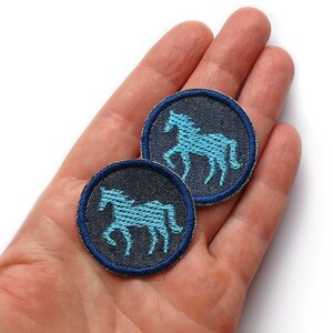 May include: Two blue denim iron-on patches with a light blue horse silhouette embroidered on each.
