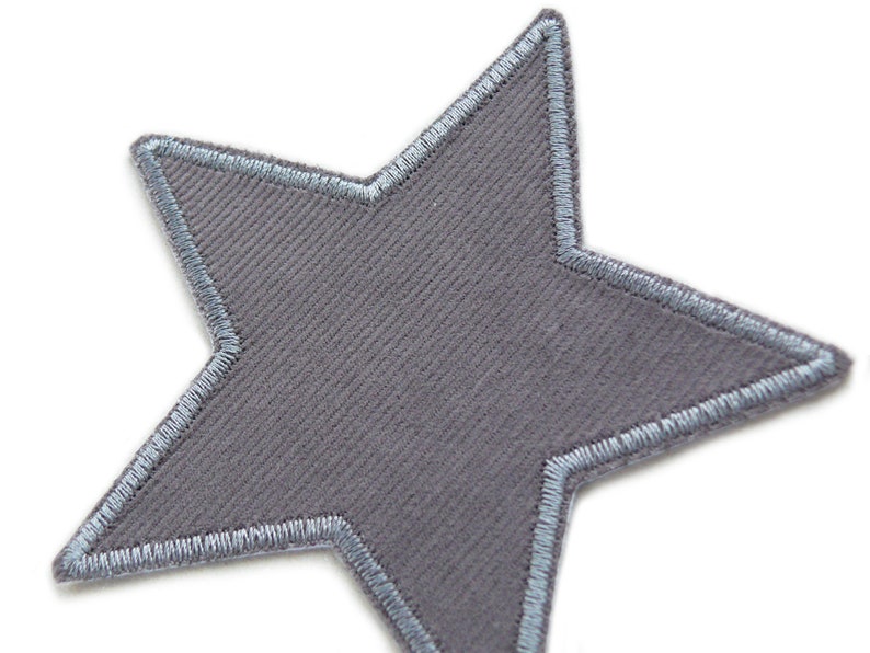 Puede incluir: Un parche gris en forma de estrella con un borde bordado azul claro.