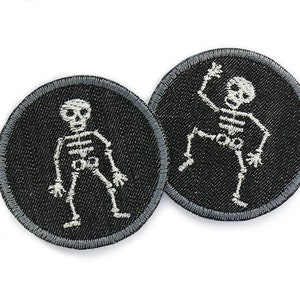 Op de afbeelding: Twee zwarte en witte geborduurde strijkpatches met skeletten. De skeletten staan in verschillende poses, één staat en de ander danst.