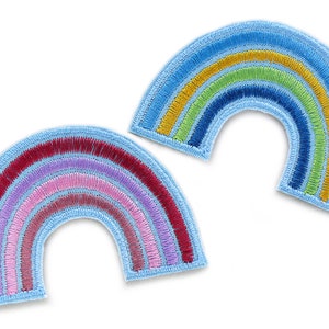Könnte beinhalten: Zwei gestickte Regenbogen-Patches. Ein Regenbogen hat rote, rosa, lila und hellrosa Streifen. Der andere Regenbogen hat blaue, grüne, gelbe und blaue Streifen. Beide Patches haben einen hellblauen Rand.