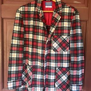Könnte beinhalten: Ein rot-weiß-schwarzer karierter Blazer mit einem Knopfverschluss und zwei aufgesetzten Taschen. Der Blazer hat ein rotes Satin-Futter und ein Etikett mit der Aufschrift "Pendleton Woolen Mills, Portland, Oregon".