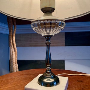 May include: A vintage table lamp with a clear glass shade, a brass base, and a white marble base.
