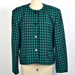May include: A green and black gingham blazer with a button front closure. The blazer has a cropped length and is made of a woven fabric.