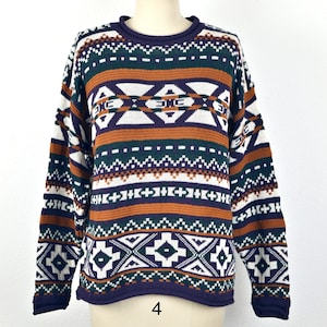 May include: A colorful sweater with a geometric pattern in shades of purple, green, white, and brown. The sweater has a crew neck and long sleeves.