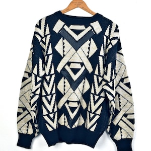 May include: Black and white geometric patterned sweater with a black leather patch on the front.