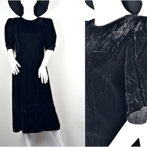 May include: A black velvet dress with puffed sleeves and a gathered skirt. The sleeves have a decorative trim of black fabric.