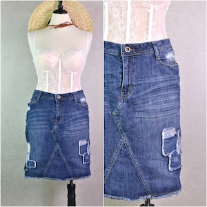 May include: A blue denim skirt with distressed details and patches. The skirt has a straight fit and a frayed hem.