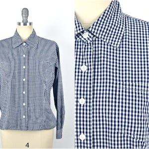 Puede incluir: Una camisa de botones azul y blanco a cuadros con mangas largas y un bolsillo en el lado izquierdo.