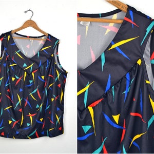 May include: A sleeveless top with a V-neck and a black background. The top has a colorful geometric pattern with red, yellow, blue, and green accents.