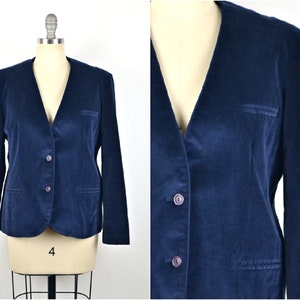 May include: A navy blue velvet blazer with a v-neck and three buttons. The blazer has two pockets on the front and long sleeves.