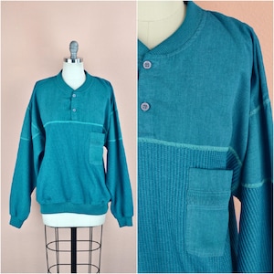 Peut inclure: Chemise à manches longues en tricot gaufré bleu sarcelle avec un plastron à un bouton et une poche plaquée sur le côté gauche.