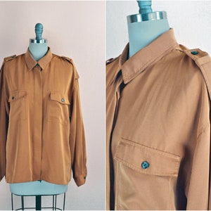 Puede incluir: Una camisa de manga larga de color marrón con botones, cuello y dos bolsillos de solapa. La camisa tiene un corte holgado y está hecha de una tela suave y sedosa.