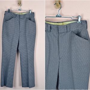 Puede incluir: Un pantalón de pierna ancha de cuadros marrones y grises. El pantalón tiene una cremallera y trabillas para el cinturón.